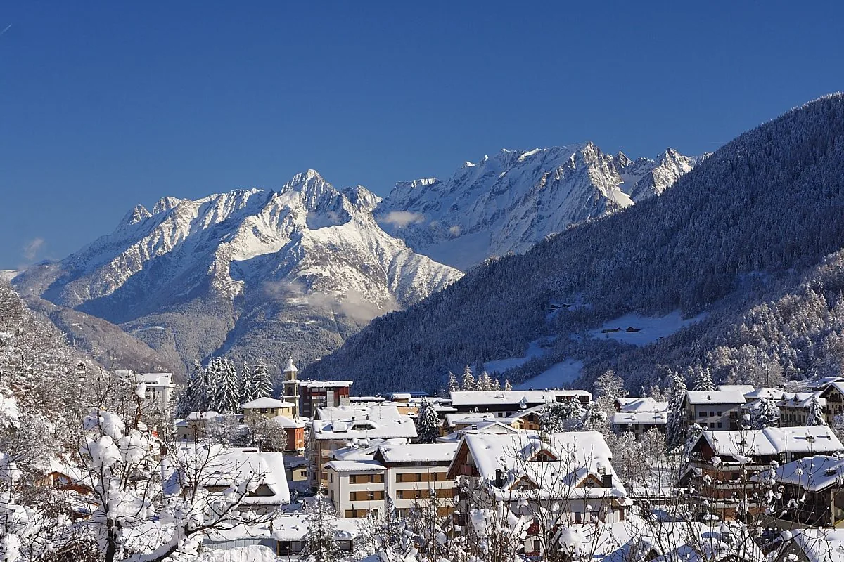 Aprica sotto la neve con i tetti imbiancati e le montagne innevate sullo sfondo