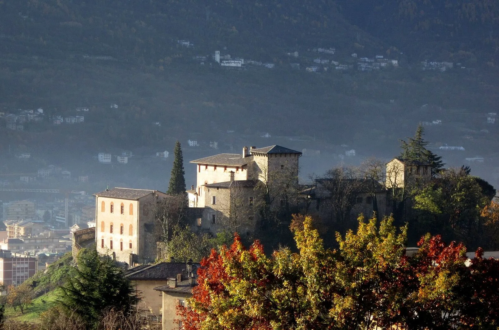 Castel Masegra a Sondrio tra gli alberi in autunno, con il versante della valle sullo sfondo